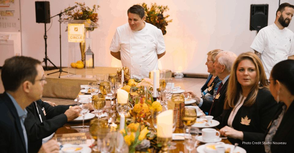 Chef greeting guests at a candlelit gala dinner table