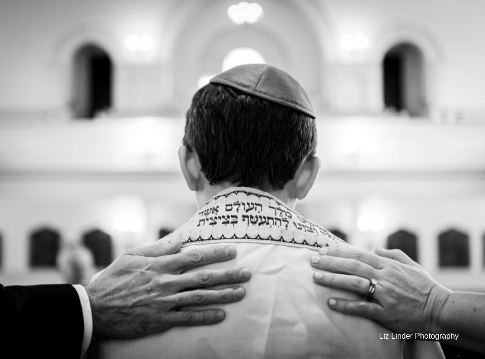 Bar Mitzvah ceremony, hands resting on the shoulders of a young man wearing a tallit