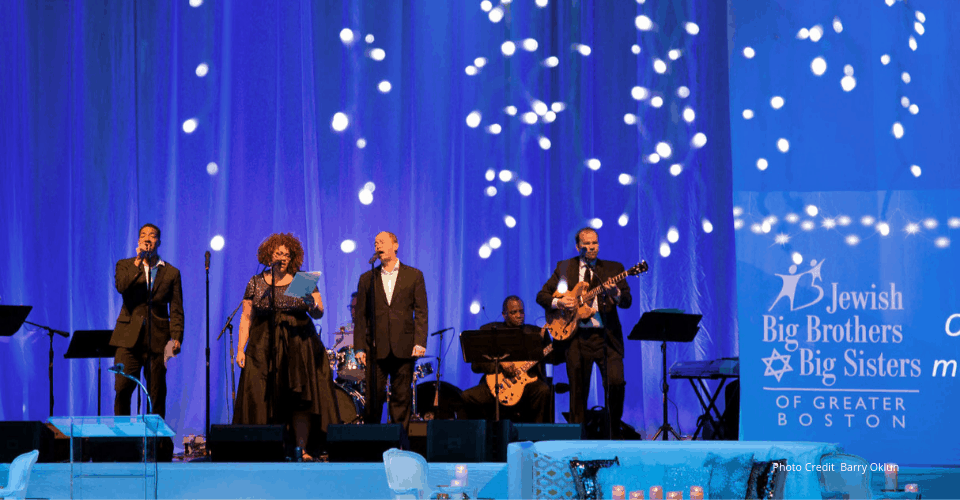 Live band performing on a blue-lit stage at a Boston gala